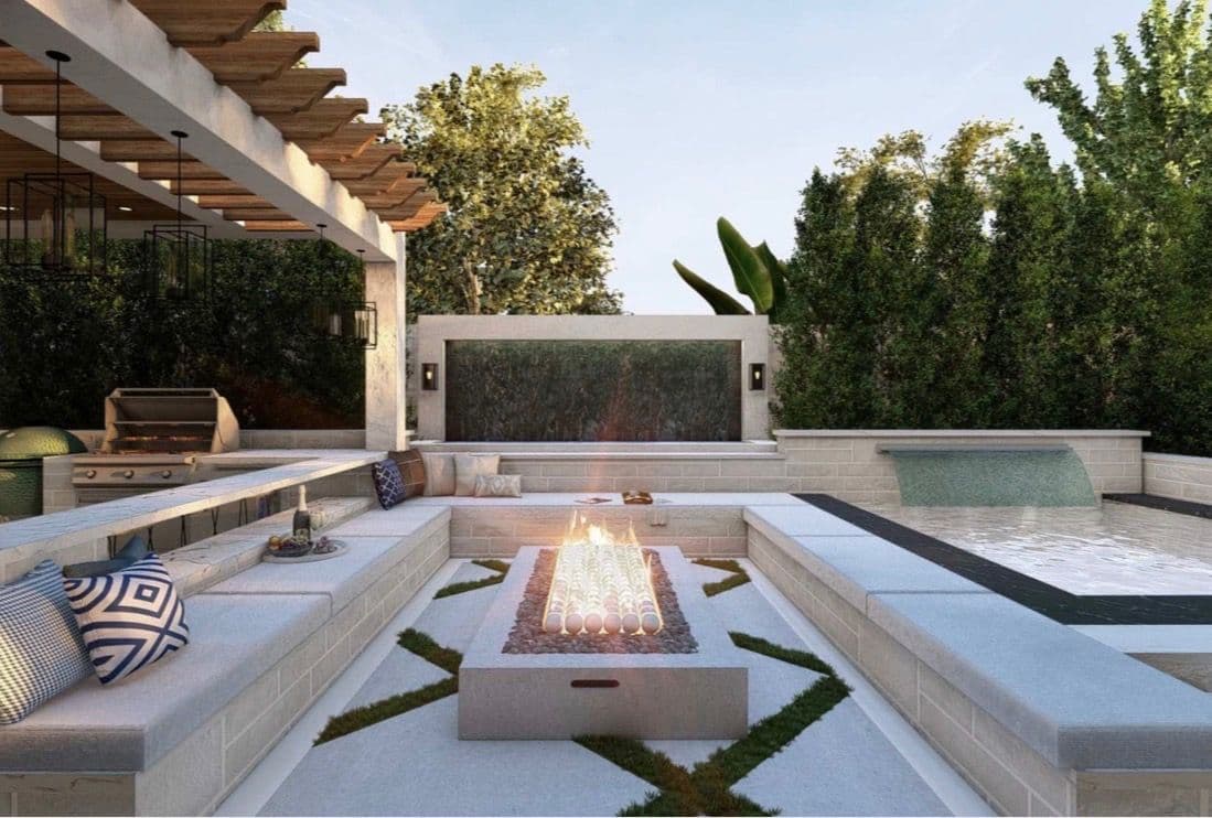 Modern outdoor patio with fire pit, seating area, grill, and lush greenery. Ideal for entertaining.